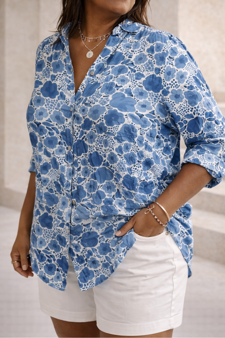 Woman wearing a blue floral shirt and white shorts in an indoor setting