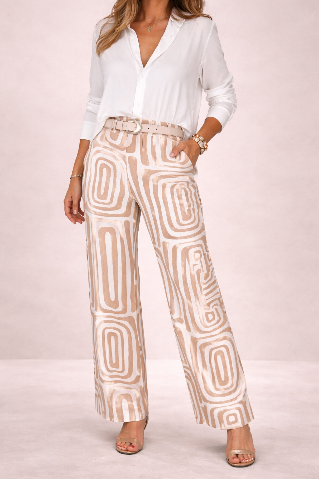 Woman wearing a white blouse and patterned pants on a light pink background