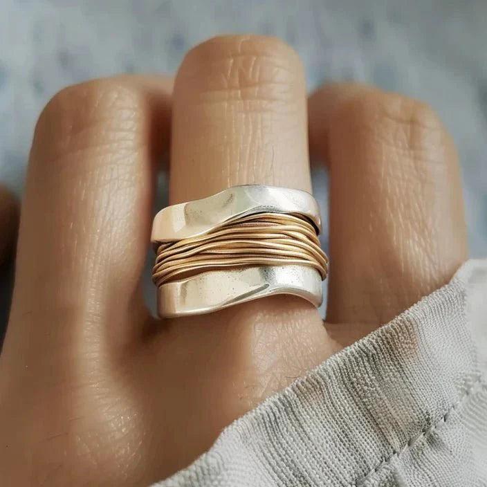 Gold and silver ring on a finger with a blurred background